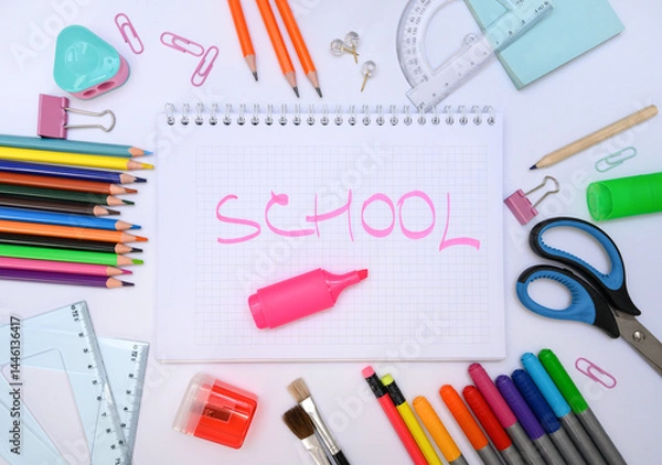 Fototapeta Top view of notebook with SCHOOL lettering surrounded by vibrant school tools. Perfect for back-to-school promotions and kids education design. Great for educational blogs or creative ads.