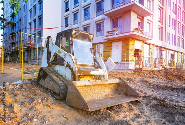 Obraz Skid steer loader on construction site. Compact Track loader, construction equipment. Road repair at construction site. Bobcat skid-steer loader on roadworks. Building construction work. Renovation.
