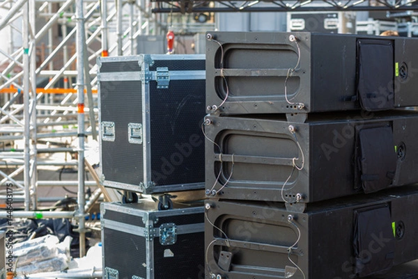Fototapeta Stacks of sound equipment and lighting gear are arranged at an outdoor venue, ready for a concert.