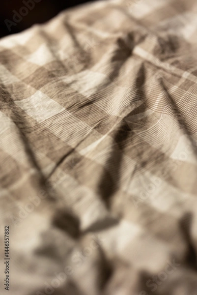 Fototapeta close-up of a soft slept-in comforter that is beige and checkered in soft moody lighting, image of a cozy blanket