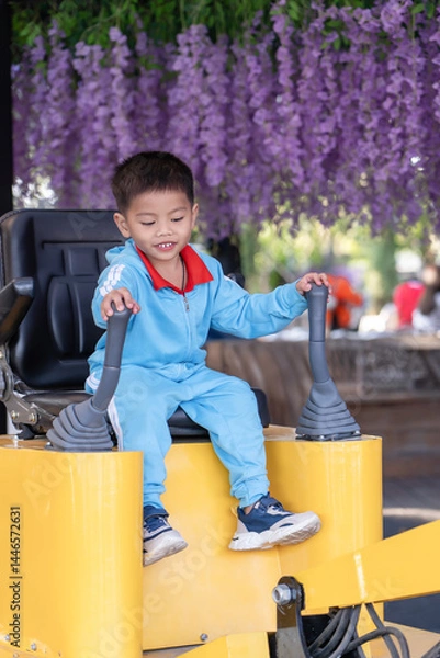Fototapeta Happy Asian boy playing Children's Playground at the public park with training in operating the excavato stock photo