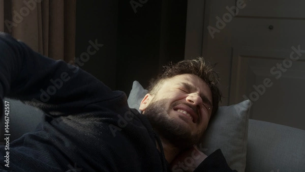 Obraz A man is laying on a couch with his head on a pillow