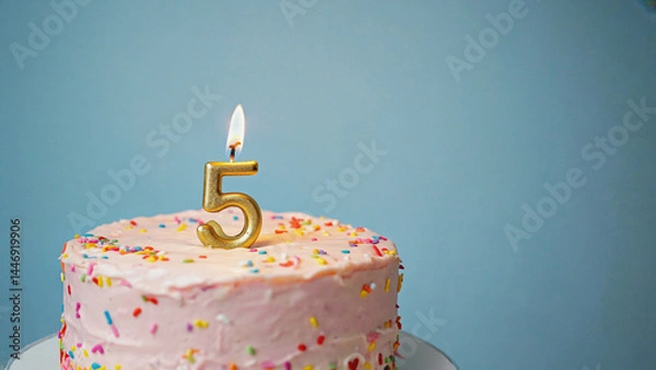Fototapeta Five Candle Celebration Cake: A vibrant cake topped with a lit candle displaying the number 5. Ideal for celebrating a milestone, with a simple yet elegant appeal.