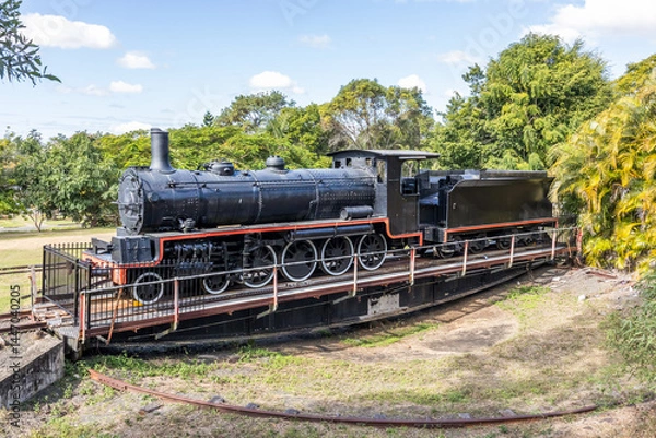 Obraz A retired old steam locomotive and coal truck on a turntable for turning trains around at the end of the line against a background of trees and sky at Imbil in Queensland, Australia.