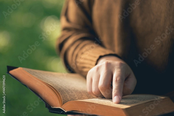 Obraz  Christian Bible Study Concepts. close up woman's hand holding and reading a book on a Sunny morning. Studying the word of God. Sharing the gospel. Followers studying the word of God. Education