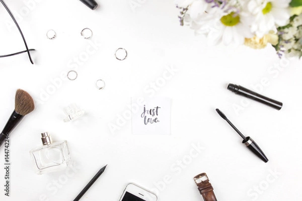 Fototapeta A bouquet of flowers with Just love written in calligraphic style on paper on flowers on a white background with female things. Flat lay, top view
