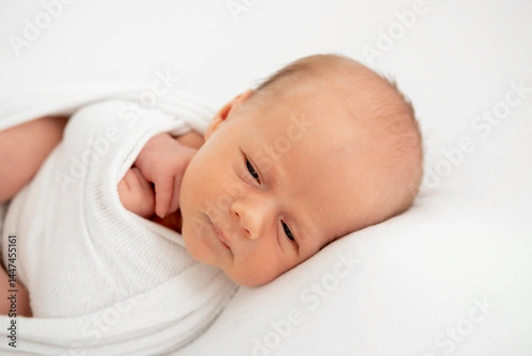 Fototapeta a newborn baby is lying in a diaper on a bed on a white isolated background, a place for text, a small baby boy is sleeping sweetly, a close-up portrait