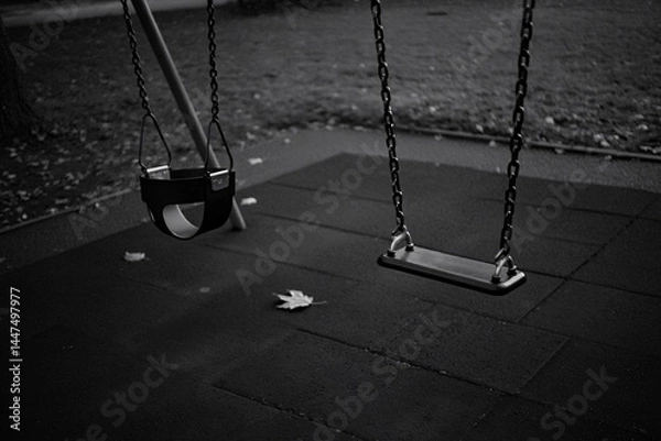 Fototapeta Empty swings in a park, suspended on a playground structure, set against a backdrop of fallen leaves.