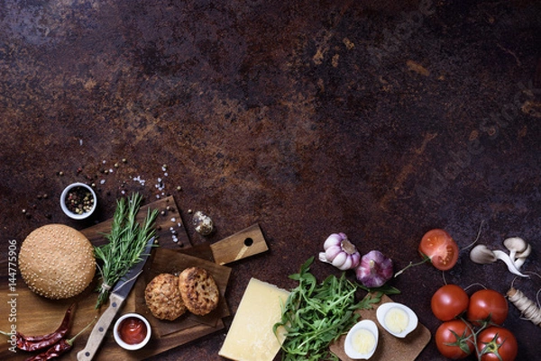 Obraz Fresh homemade burger on dark serving board with beef, tomatoes, cheese and eggs over dark background. Top view, copy space.