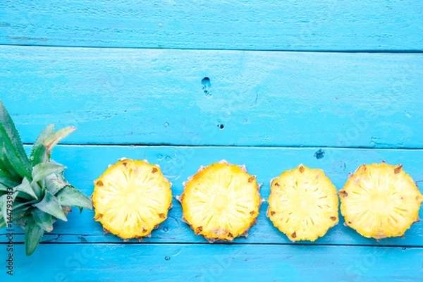 Fototapeta the summer pineapple is slice for eat on blue wooden background. copy space for designer