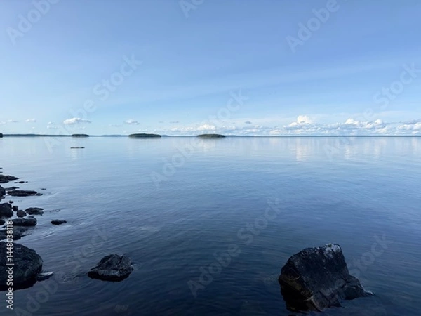 Obraz Calm lake scene, with reflections on the water, small islands, and a bright blue sky in Sweden.