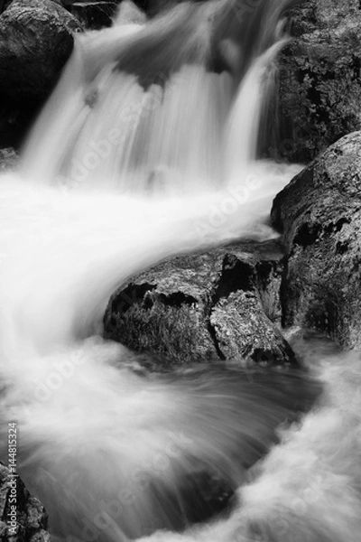 Obraz river rocks in smooth satin water flow of waterfall in black and white in long exposure
