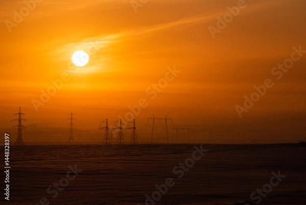 Fototapeta Russia. The South of Western Siberia. High-voltage metal structures against the background of a crimson dawn winter sky.