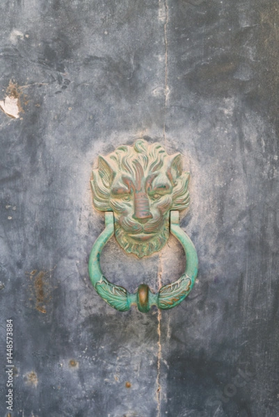 Obraz Antique lion head door knocker on aged metal surface. Ideal for architecture blogs, vintage design themes, or restoration project visuals.