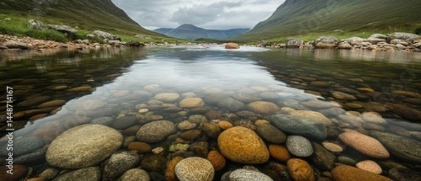 Fototapeta A river with a rocky bottom and a reflection of the mountains in the water