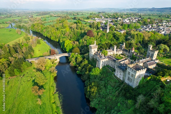 Fototapeta  Aerial view of historic Lismore Castle and the surrounding townscape in County Waterford, Ireland, with lush spring greenery, the River Blackwater, and rolling countryside under soft evening light.
