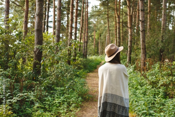 Fototapeta A girl in a poncho and a hat in forest