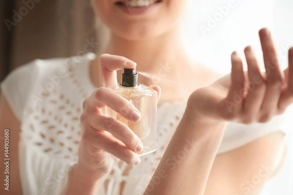 Obraz Piękna młoda kobieta z butelką perfum w domu, zbliżenie