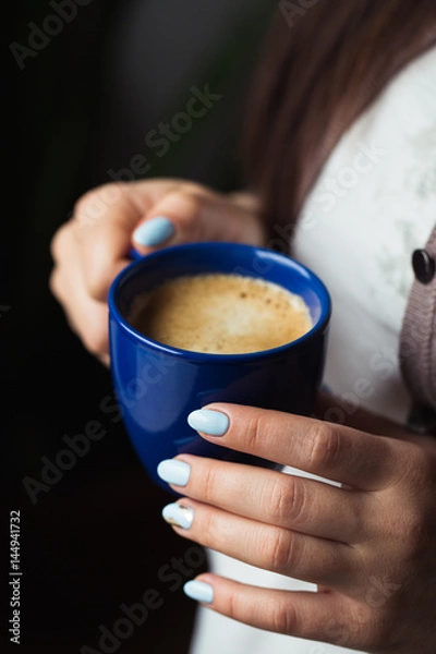 Fototapeta Girl with blue manicure holds a blue cup of coffee