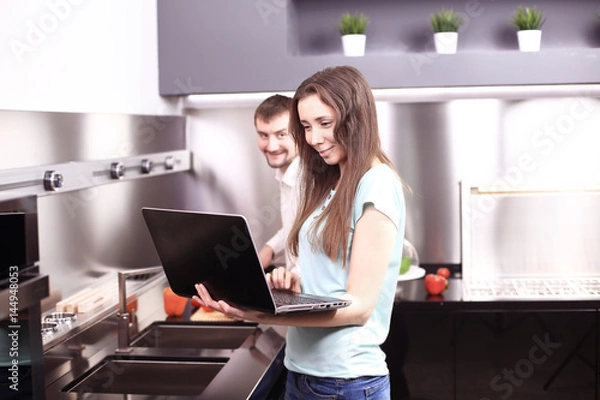 Fototapeta Couple in front laptop computer in the kitchen