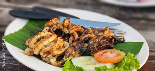Fototapeta Fresh Grilled caramari squid with sweet sauce serving on banana leave on timber table