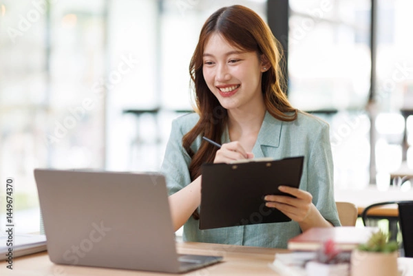 Fototapeta Young business woman using calculator and laptop for doing math finance on an office desk, tax, report, accounting, statistics, and analytical research concept
