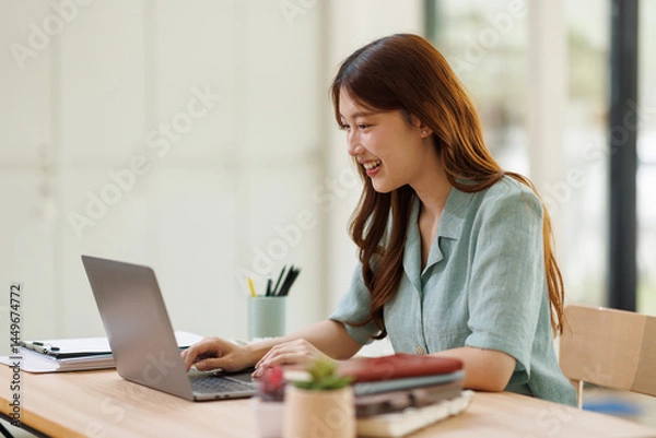 Fototapeta Young business woman using calculator and laptop for doing math finance on an office desk, tax, report, accounting, statistics, and analytical research concept
