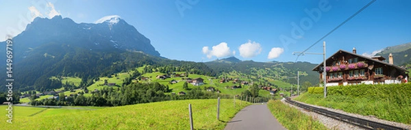 Fototapeta walkway beside railroad Grindelwald, chalet with geranium flowers, Eiger and Wetterhorn mountain