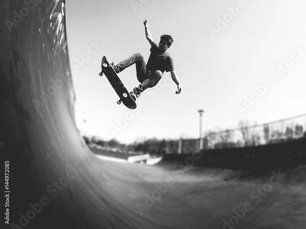 Fototapeta Skateboarder robi ollie na rampie - czarno-biały