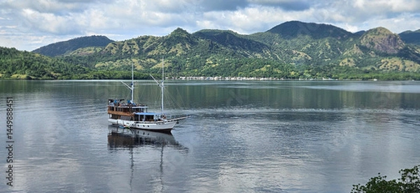 Fototapeta Phinisi boat sailing in the Flores sea of the Komodo national park with mountain island background.