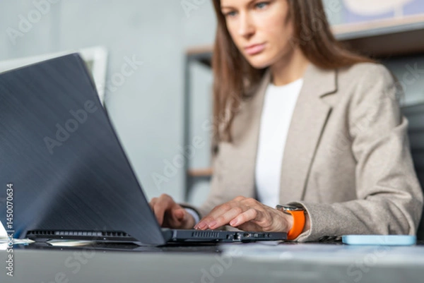 Fototapeta Serious focused businesswoman working in an office with laptop computer