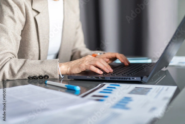 Fototapeta Woman working with laptop and documents analyzing data or writing reports Workplace office or home
