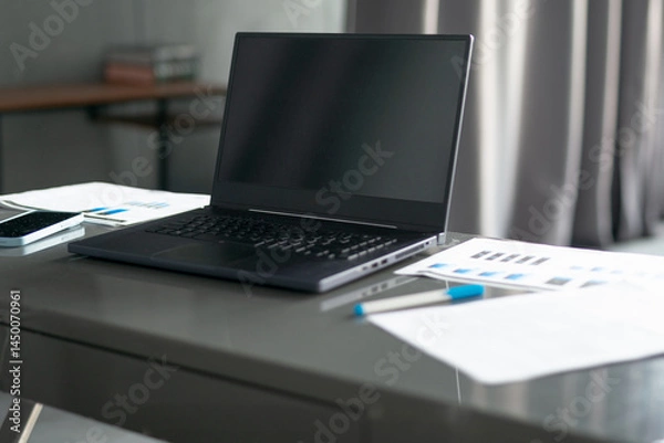 Fototapeta Laptop documents papers on desk workspace in office or at home