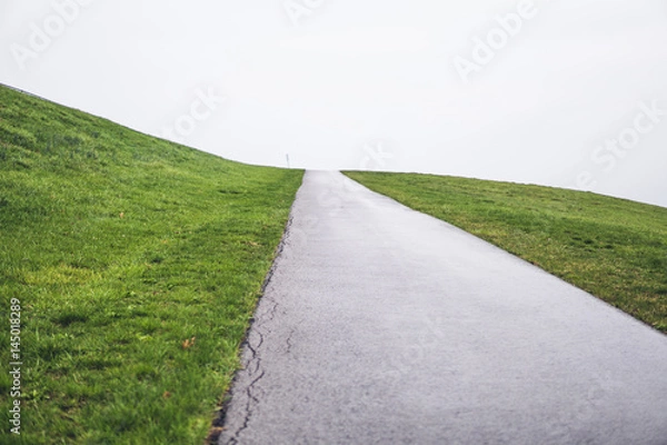 Fototapeta Road heading up in green grass, minimalistic background
