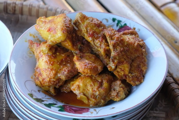 Fototapeta spicy balado chicken on a plate. spicy chicken seasoned with chili, turmeric, ginger, shallots, garlic. balado ayam.