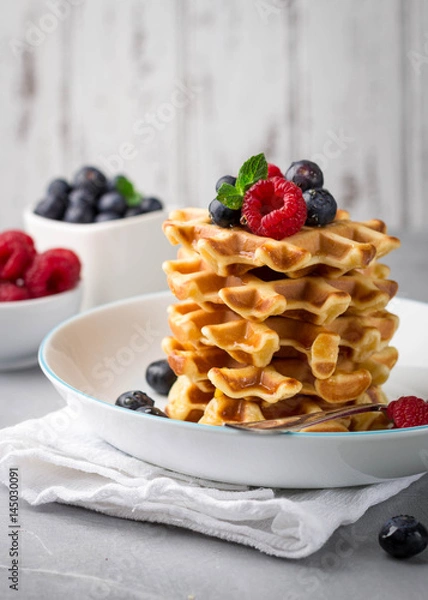Fototapeta Stack of delicious homemade waffles with fresh berries on light background