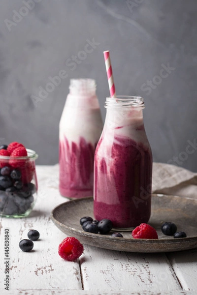Fototapeta Healthy berry smoothie with yogurt in bottle on light concrete background