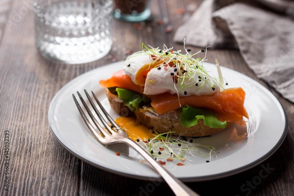 Fototapeta Delicious toast with salad, salted salmon and poached egg on rustic background