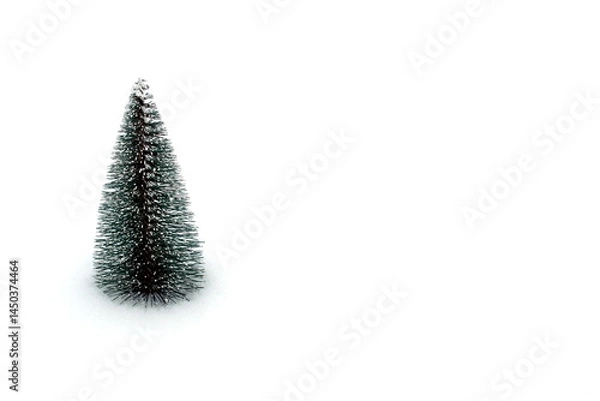 Obraz On a white background in the snow stands a small toy fir tree.