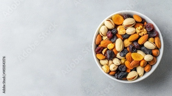 Fototapeta A beautiful bowl of mixed nuts and dried fruits on a light gray background for healthy snacking