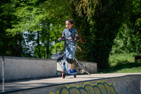 Fototapeta view of a child riding a scooter in a skate park