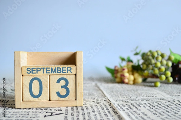 Fototapeta September 3, Calendar cover design with number cube with fruit on newspaper fabric and blue background.	