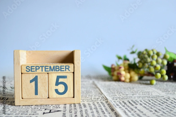 Fototapeta September 15, Calendar cover design with number cube with fruit on newspaper fabric and blue background.	