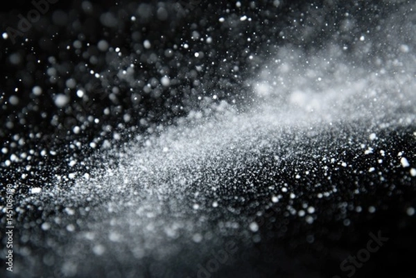 Fototapeta An abstract close-up shot of particles in motion, suggesting snow, dust, or other fine matter against a dark background.