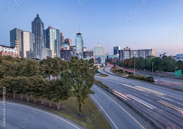Fototapeta Downtown Atlanta Skyline showing several prominent buildings, highways, cars, light trails and hotels under a blue sky.