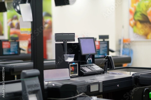 Fototapeta Empty cash desk with computer screen and card payment terminal on blurry background
