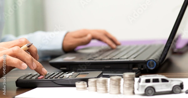 Fototapeta businessman using calculator and calculated car loan finance interest,at workplace, financial, refinance, accounting and banking concept	