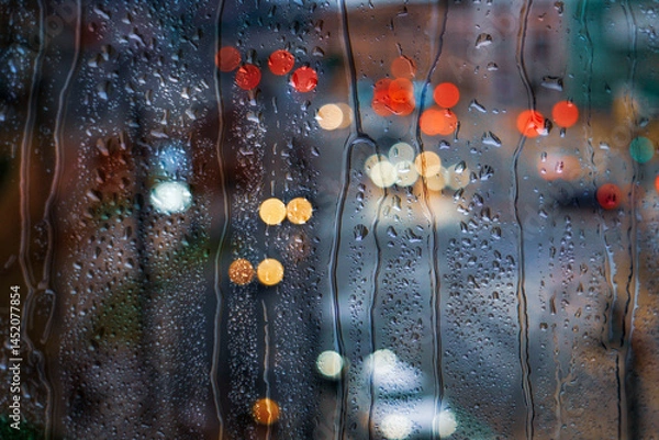 Fototapeta raindrops on the window and multi colored street lights at night background