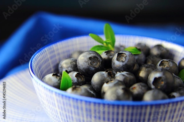 Obraz свежая голубика в голубой миске с зеленым листом