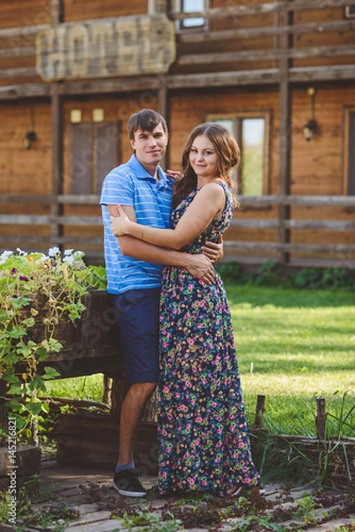 Fototapeta Romantic young couple hugging each other on the background of the hotel in a rustic style.